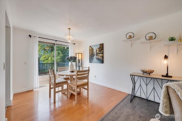 dining space featuring light wood-type flooring, a chandelier, and baseboards