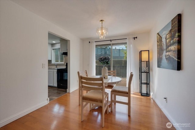 dining area with a chandelier, light wood-type flooring, and baseboards