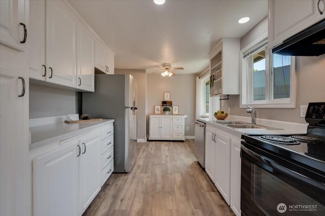 kitchen with appliances with stainless steel finishes, white cabinets, a sink, light countertops, and under cabinet range hood