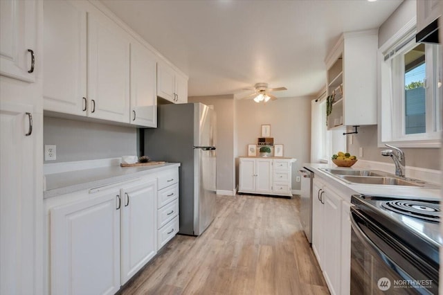 kitchen with appliances with stainless steel finishes, a sink, white cabinetry, and light countertops