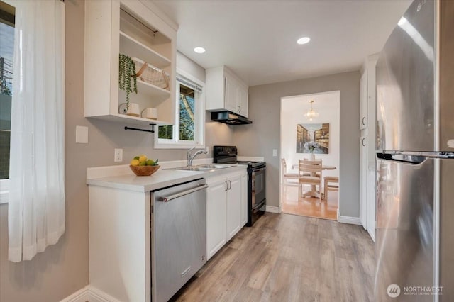 kitchen with stainless steel appliances, a sink, under cabinet range hood, light wood finished floors, and light countertops