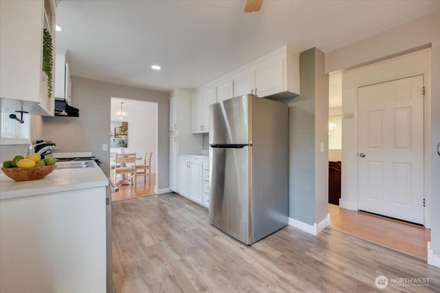 kitchen with freestanding refrigerator, white cabinetry, light countertops, light wood finished floors, and recessed lighting
