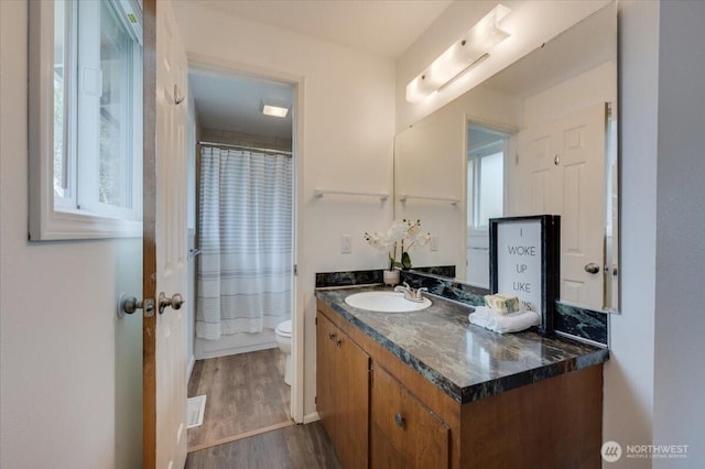 bathroom with toilet, vanity, wood finished floors, and curtained shower