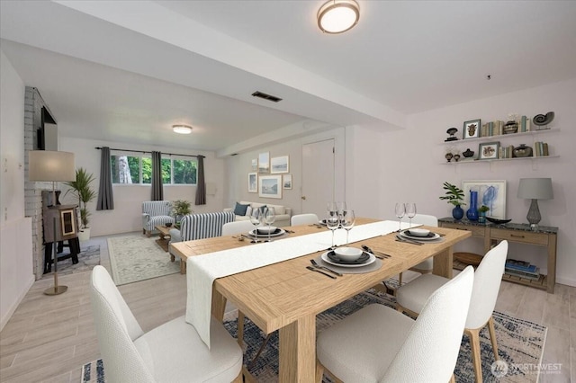 dining space featuring a wood stove, light wood finished floors, and baseboards