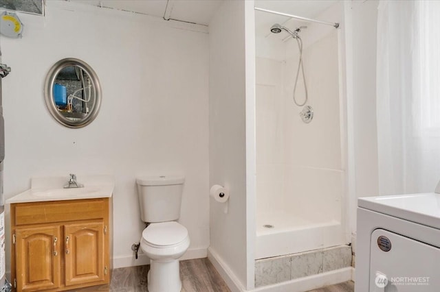 bathroom with washer / dryer, a stall shower, vanity, toilet, and wood finished floors