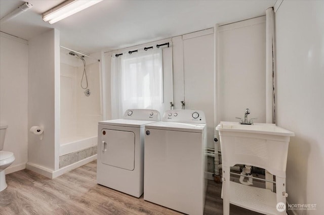 laundry room with independent washer and dryer, light wood-type flooring, and baseboards