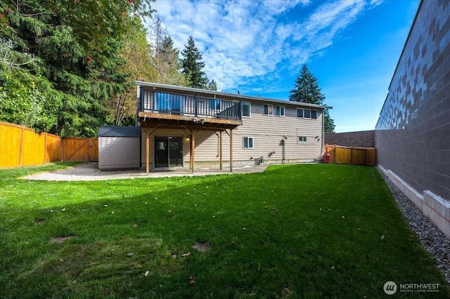 rear view of house featuring a shed, a wooden deck, an outbuilding, and a patio area