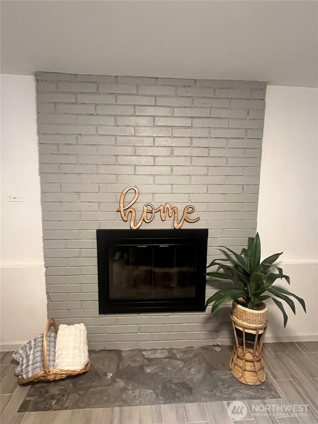 detailed view of a fireplace, wood tiled floors, and baseboards