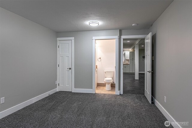 unfurnished bedroom with carpet floors, baseboards, a textured ceiling, and connected bathroom