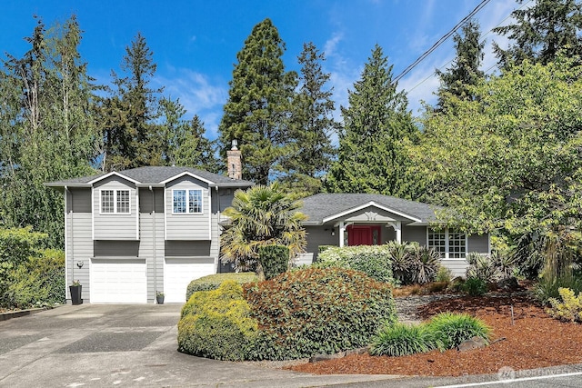 view of front of home with concrete driveway, a chimney, and a garage