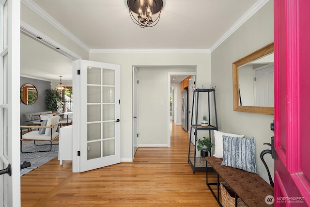 corridor with a chandelier, wood finished floors, ornamental molding, and baseboards
