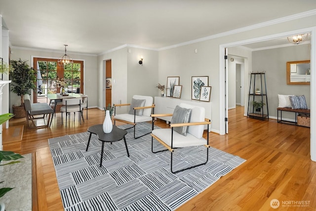living area with a chandelier, light wood-style flooring, baseboards, and ornamental molding