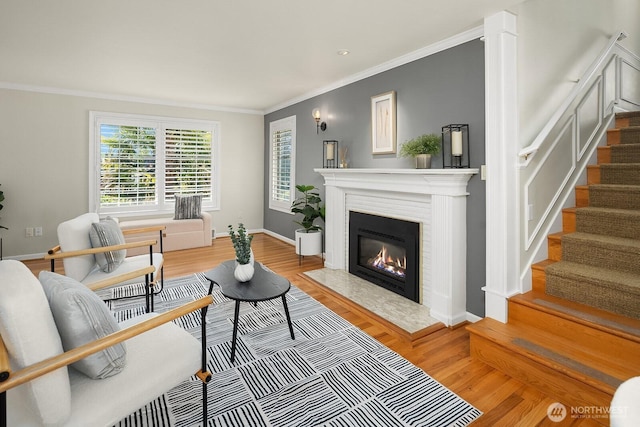 living area with stairs, crown molding, light wood-style floors, a fireplace, and baseboards