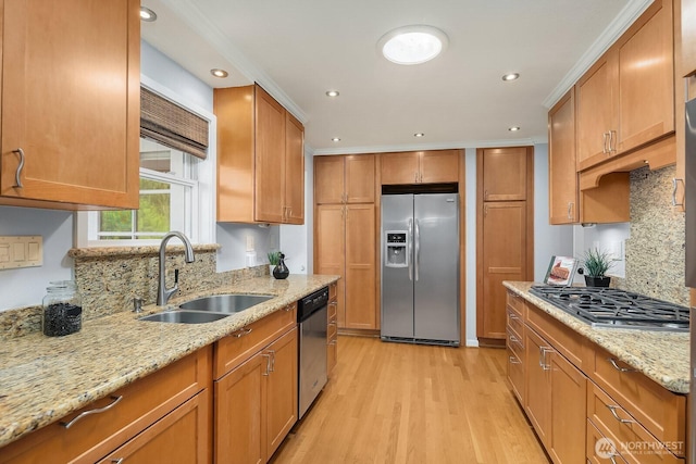 kitchen featuring appliances with stainless steel finishes, a sink, light wood-style flooring, brown cabinets, and recessed lighting