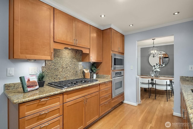 kitchen with appliances with stainless steel finishes, light wood-type flooring, crown molding, brown cabinetry, and decorative backsplash