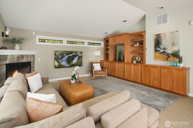living area with light colored carpet, vaulted ceiling, a tiled fireplace, and baseboards