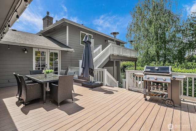 wooden deck featuring outdoor dining space, stairway, and area for grilling