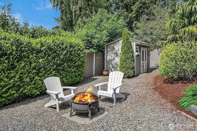 view of patio with an outdoor fire pit, a storage shed, and an outbuilding