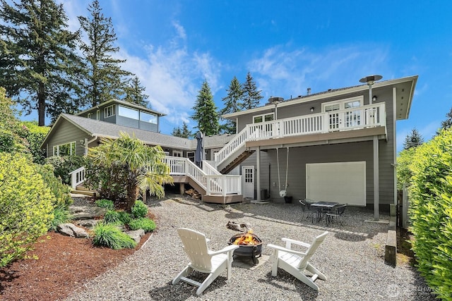 back of house featuring an outdoor fire pit, stairs, a garage, and a deck