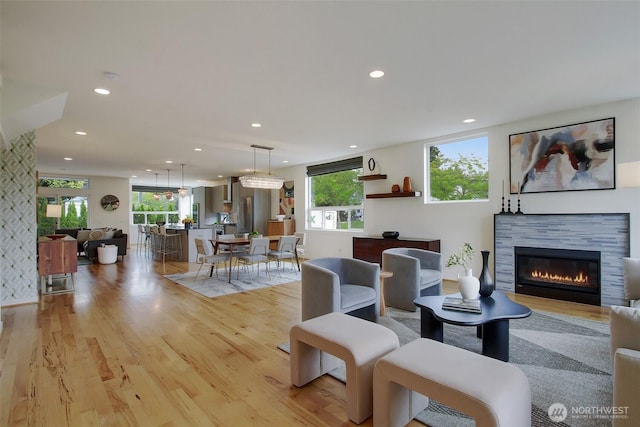 living room with recessed lighting, light wood-style floors, and a glass covered fireplace