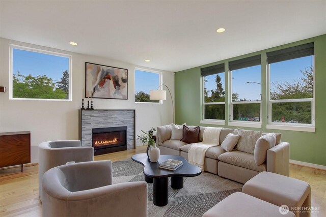living area featuring light wood-type flooring, recessed lighting, and a glass covered fireplace