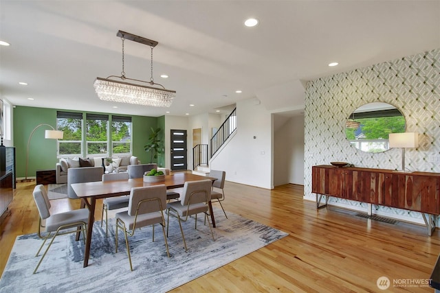 dining room with an accent wall, light wood-style floors, plenty of natural light, recessed lighting, and stairway