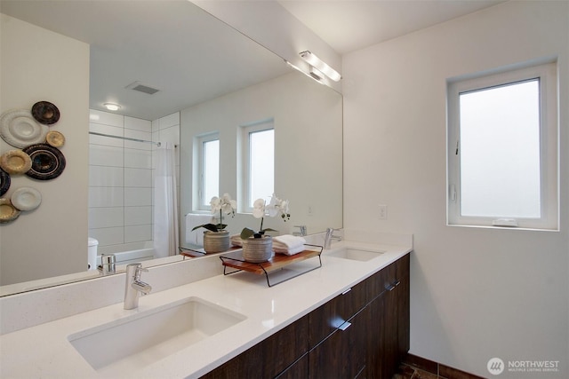 bathroom featuring double vanity, shower / tub combo with curtain, and toilet