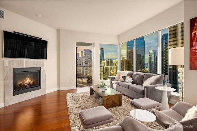 living room featuring wood finished floors, a premium fireplace, a view of city, and plenty of natural light