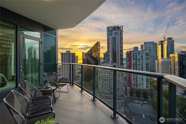 balcony at dusk featuring a skyline view