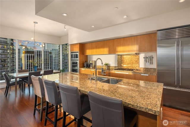 kitchen featuring a sink, built in appliances, brown cabinets, modern cabinets, and recessed lighting
