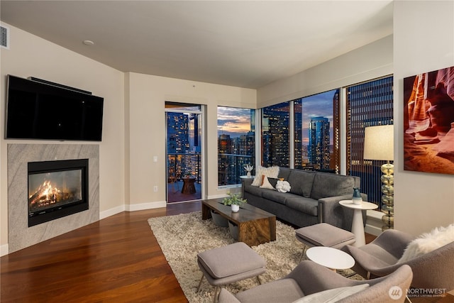 living room featuring wood finished floors, a glass covered fireplace, and baseboards