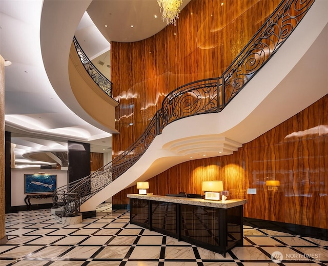 common area featuring stairway, a high ceiling, and wood walls