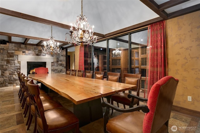 dining room with a chandelier, a stone fireplace, beam ceiling, baseboards, and wallpapered walls