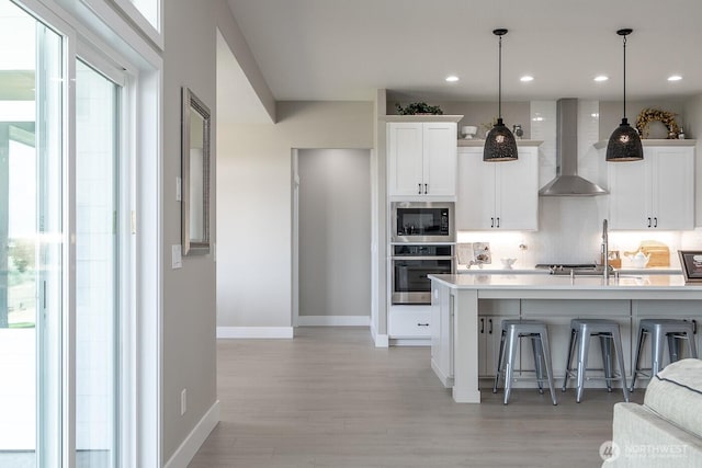 1196 8th Ave NE, Ephrata, WA 98823 - kitchen with appliances with stainless steel finishes, wall chimney exhaust hood, a breakfast bar, light wood-type flooring, and recessed lighting