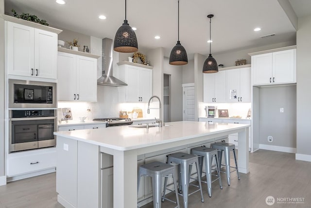 1196 8th Ave NE, Ephrata, WA 98823 - kitchen with a sink, appliances with stainless steel finishes, wall chimney range hood, light wood-type flooring, and recessed lighting