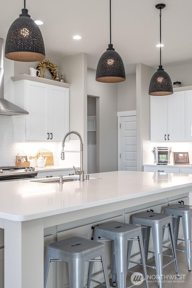 1196 8th Ave NE, Ephrata, WA 98823 - kitchen with a sink, wall chimney exhaust hood, decorative backsplash, a kitchen bar, and white cabinets