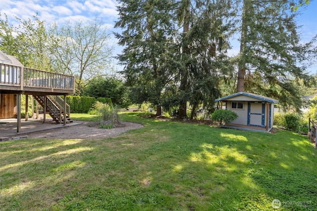view of green lawn featuring a shed, stairway, a wooden deck, an outbuilding, and view of scattered trees