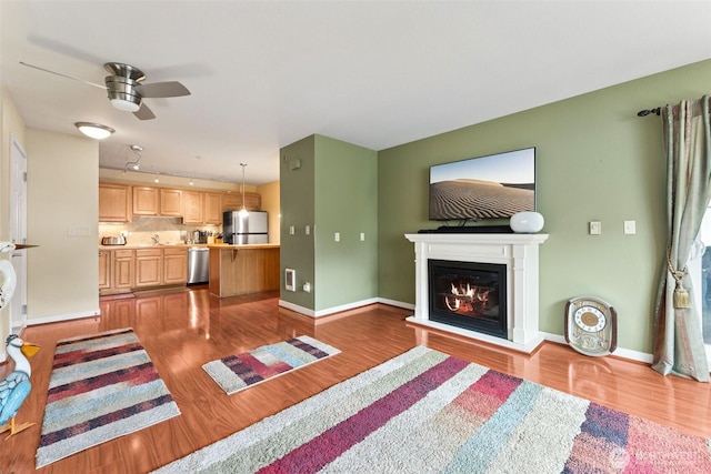 13405 97th Ave E Unit 107, Puyallup, WA 98373 - living room featuring wood finished floors, a ceiling fan, a glass covered fireplace, and baseboards