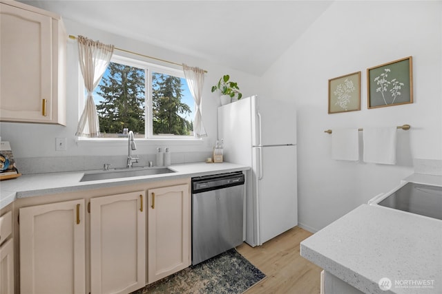 kitchen with dishwasher, a sink, freestanding refrigerator, light wood-type flooring, and light countertops