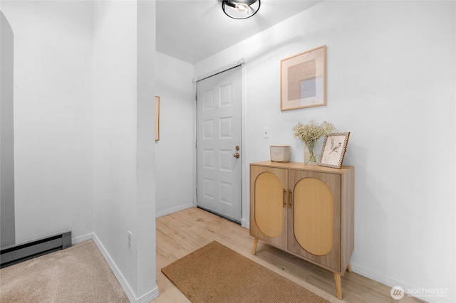 doorway featuring baseboards, light wood-type flooring, and a baseboard radiator