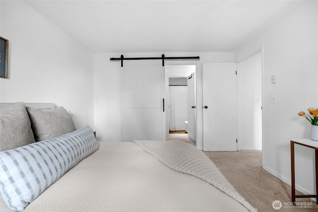 carpeted bedroom with a barn door and baseboards