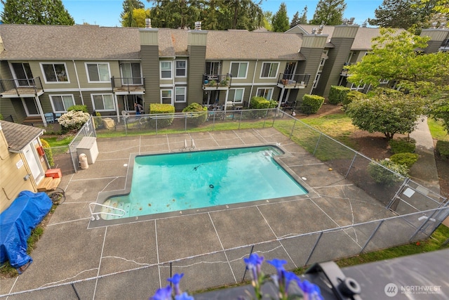 community pool featuring fence, a residential view, and a patio