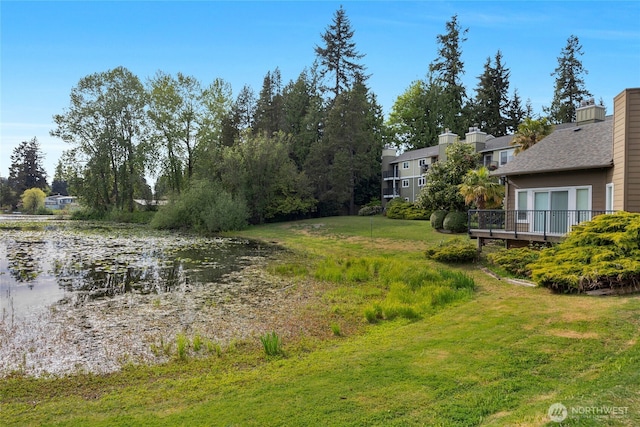 view of green lawn featuring a water view