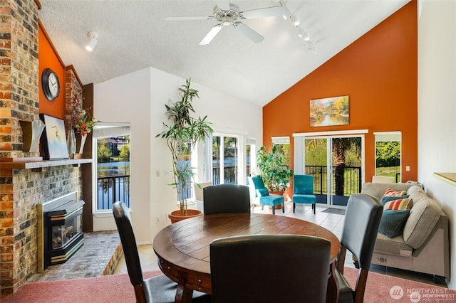 dining room featuring high vaulted ceiling, a brick fireplace, ceiling fan, rail lighting, and tile patterned floors