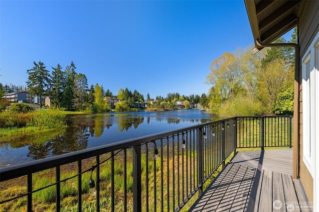 balcony featuring a water view and view of wooded area