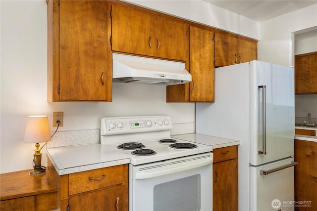 4414 Merlie Ave NE, Bremerton, WA 98310 - kitchen with white appliances, under cabinet range hood, light countertops, and brown cabinetry
