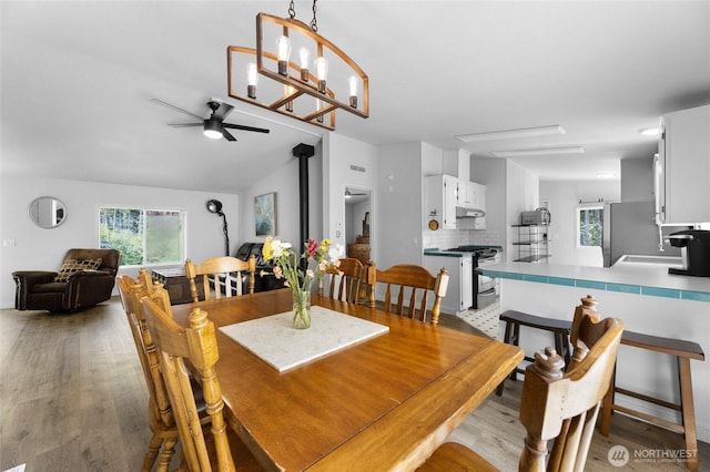 16037 Vail Loop Rd SE, Rainier, WA 98576 - dining area with a wood stove, plenty of natural light, ceiling fan, wood finished floors, and vaulted ceiling