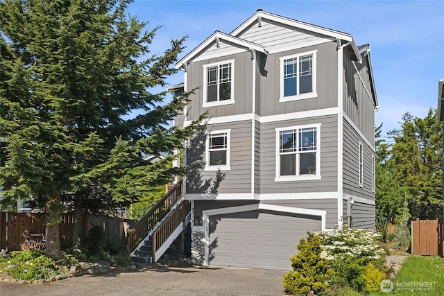 view of front of home featuring board and batten siding, fence, a garage, and driveway