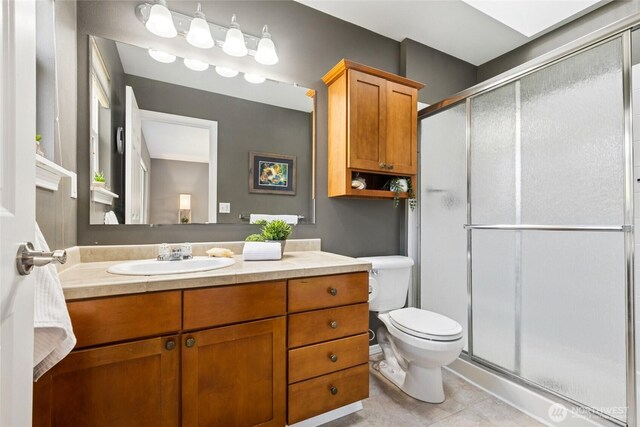 bathroom with a stall shower, toilet, tile patterned flooring, and vanity