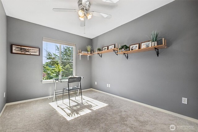 carpeted office space with a ceiling fan and baseboards